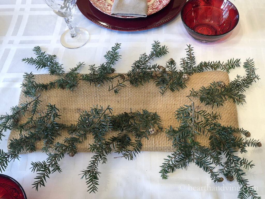 A burlap wrapped piece of wood with some evergreen branches set all along the edge.