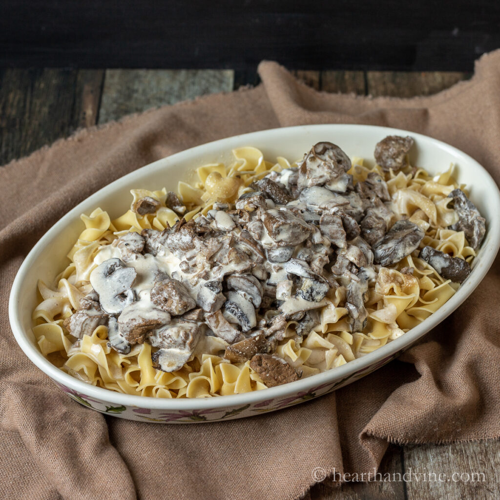 Oval dish with egg noodles, beef and mushrooms in a creamy sauce.