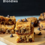 Salted caramel blondies on a wooden tray with chocolate chips scattered around.