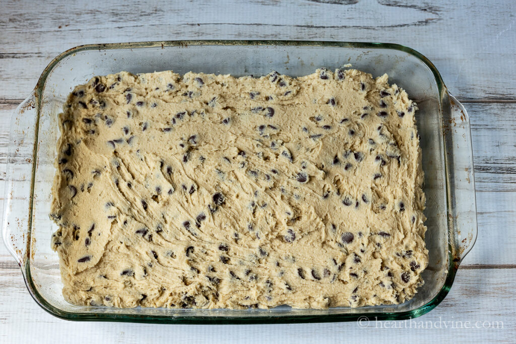 Blondie dough spread into a glass baking dish.