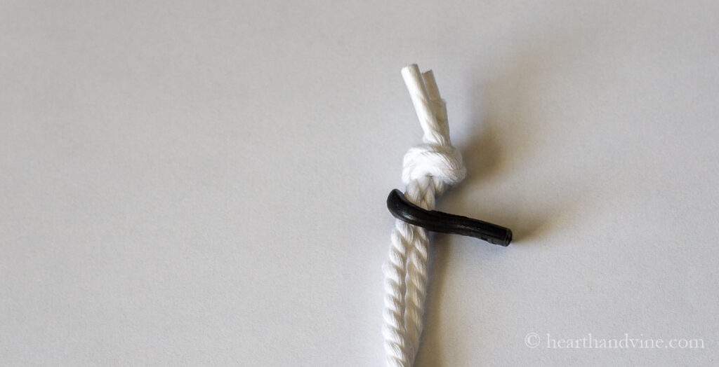 Two white cords threaded through a zipper pull hole and knotted on the ends.
