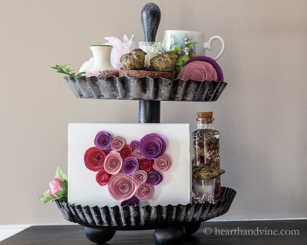 Two tiered tray in a Valentine's Day theme with paper hearts, birds, flowers and candles.