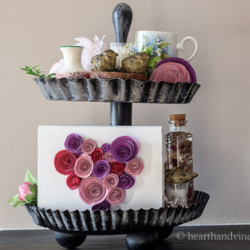 Two tiered tray in a Valentine's Day theme with paper hearts, birds, flowers and candles.