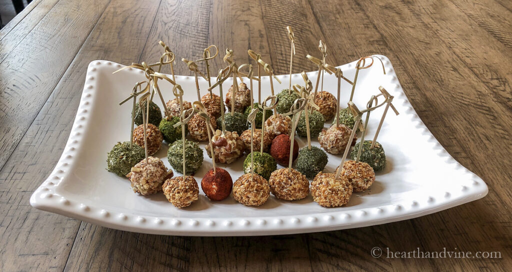 Mini cheese balls with bamboo toothpicks on a large white tray.