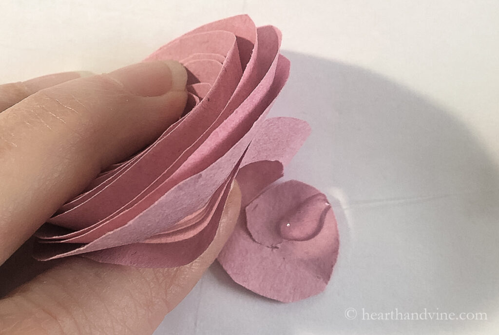 Hot glue on the end of the rolled paper flower to secure it together.