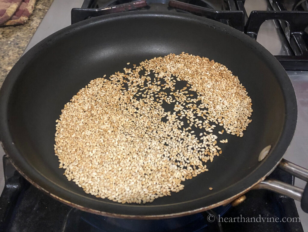Sesame seeds toasting in a non-stick pan.