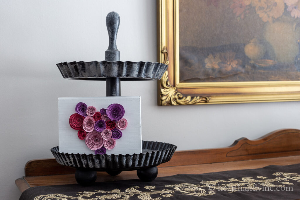 Paper flowers in a heart shape on wood sitting on a 2-tiered tray.