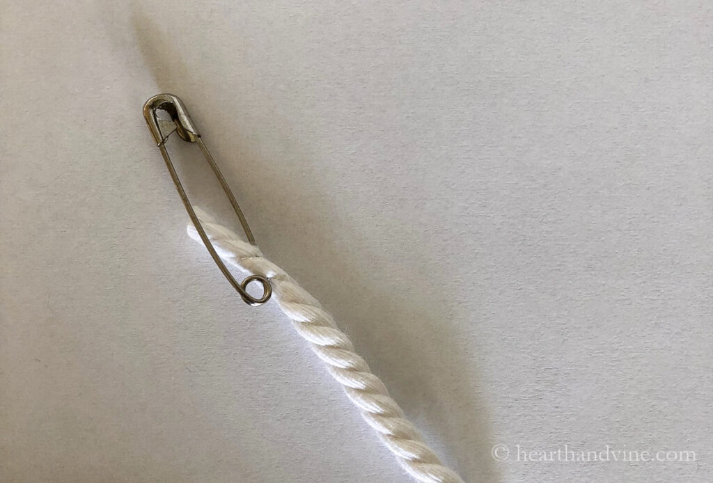 Large safety pin on the end of a length of white craft cord.