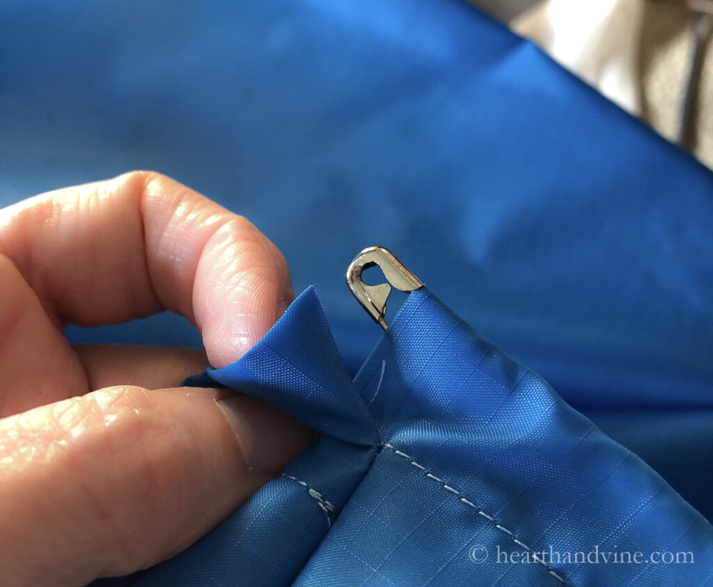 Safety pin coming out of the end of a fabric channel.