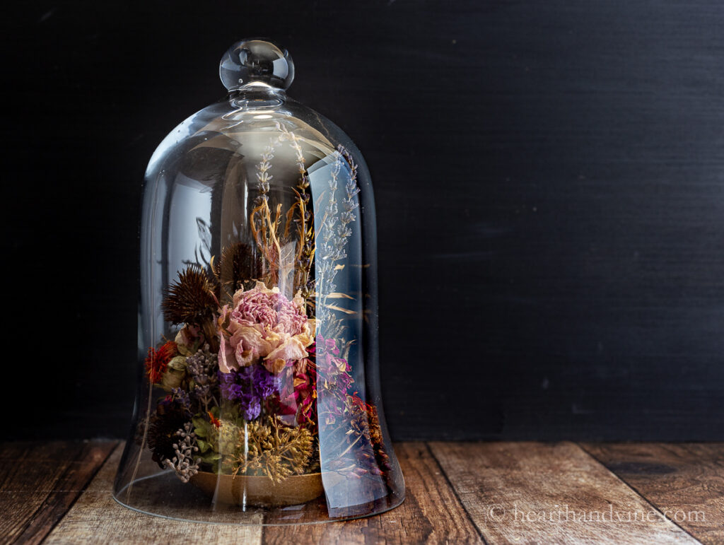 Glass cloche covering a tight dried flower arrangement.