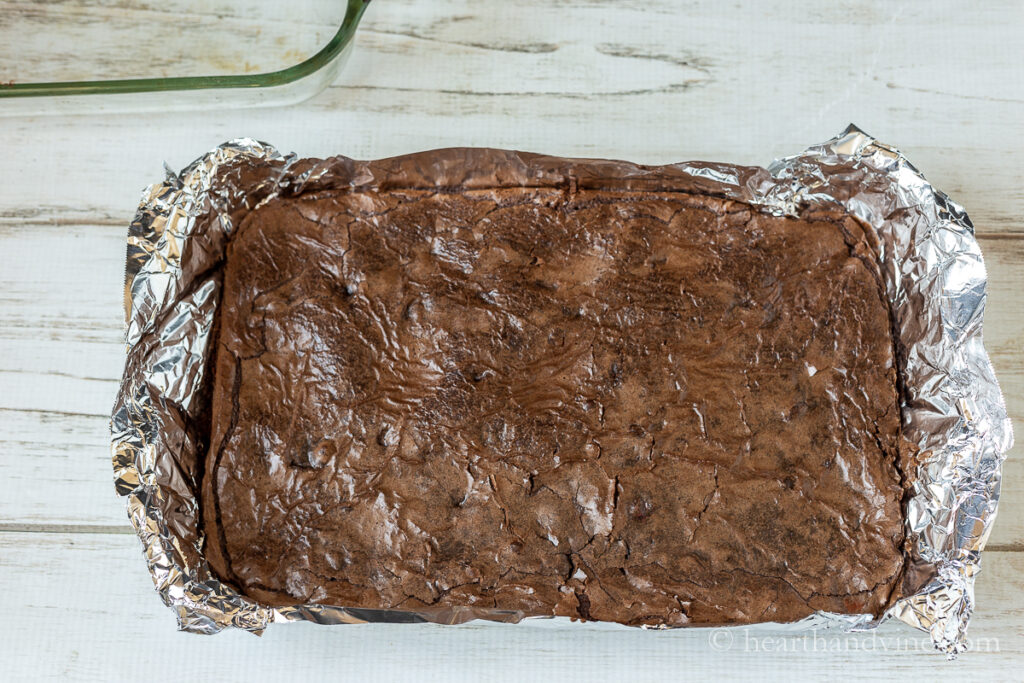 Foil lifted out of pan with baked brownies on top.