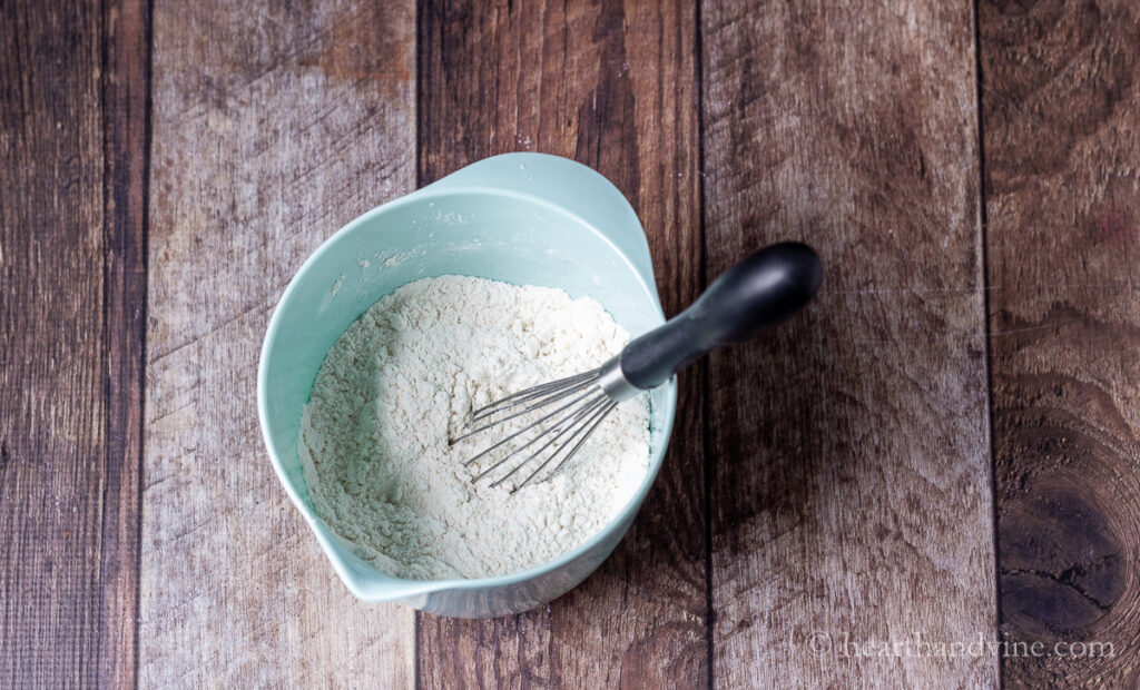 Flour mixture with a whish in a light blue mixing bow.