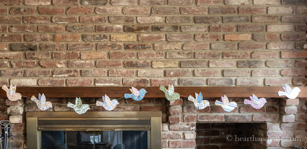DIY paper garland with colorful birds on the mantel for spring.