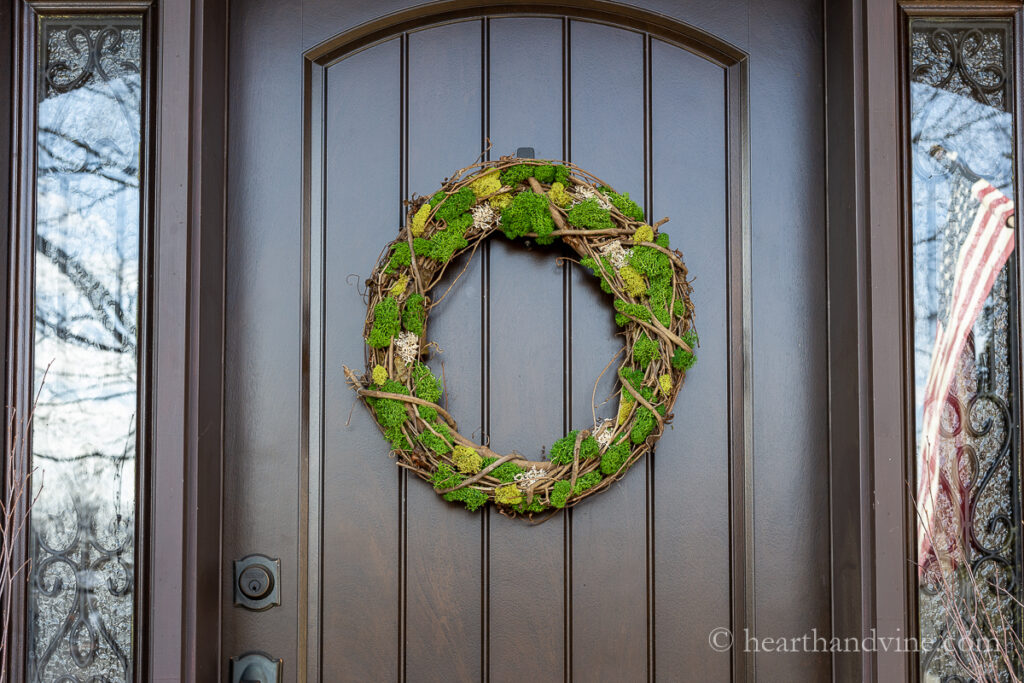 Brown front door with moss covered wreath.
