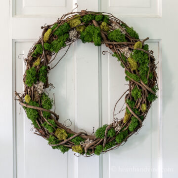 Grapevine wreath with different mosses on a white door.