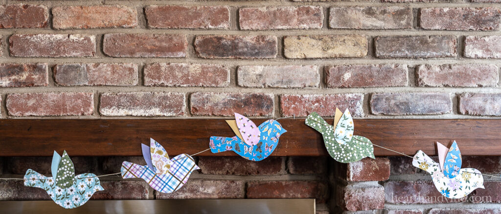 DIY paper garland with colorful birds on the mantel for spring.