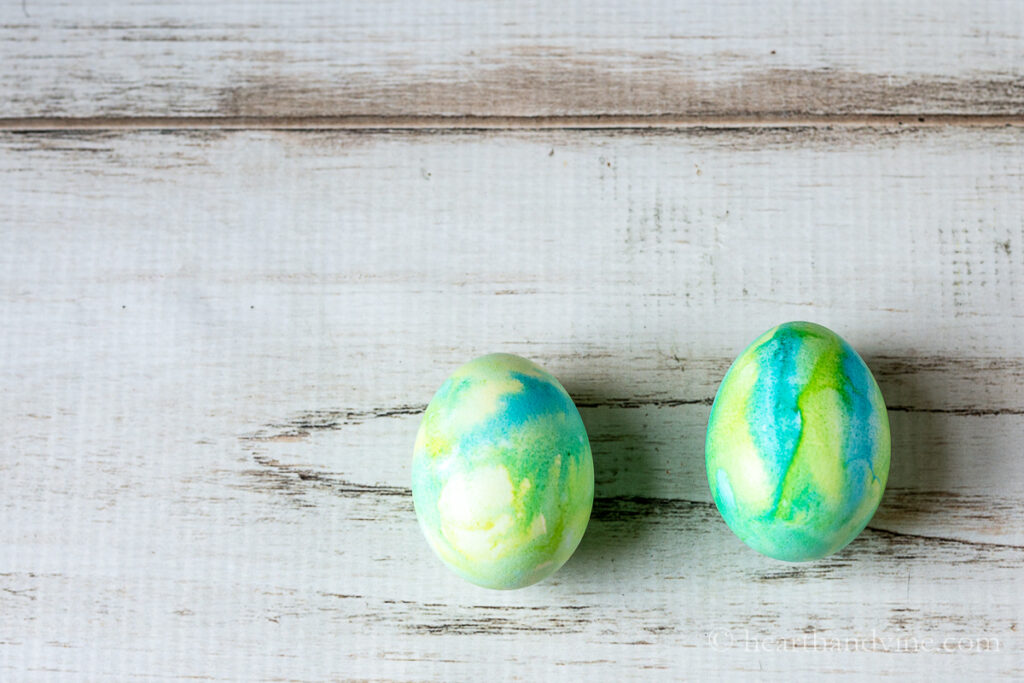 Watercolor Easter eggs in shade of blue, green and yellow stripes bleeding together.