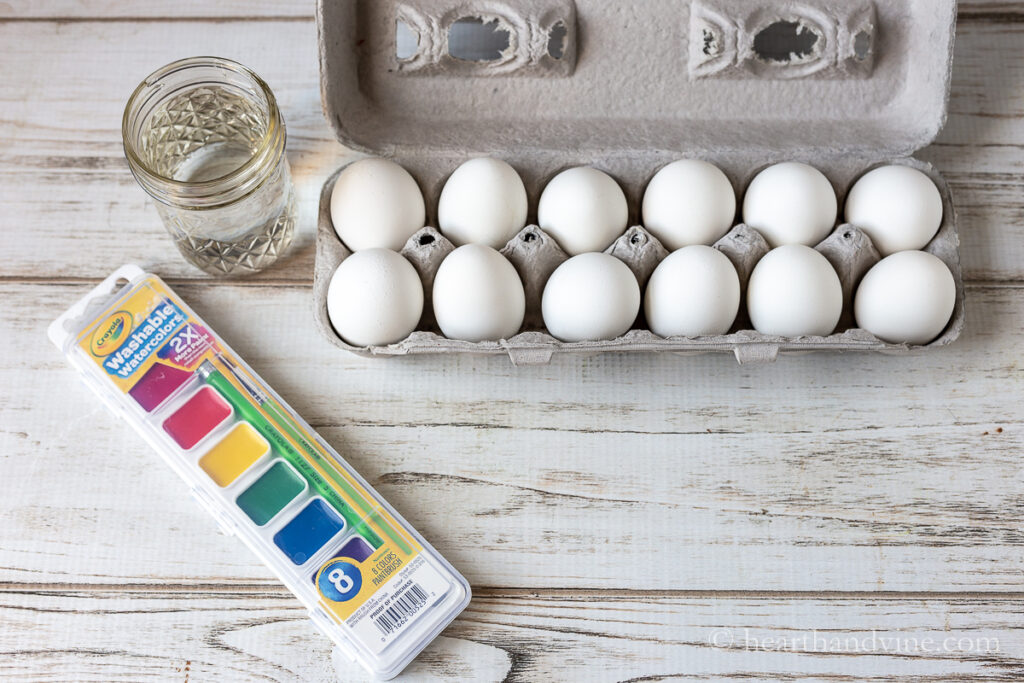A children's watercolor set, a jar of water and a carton of boiled eggs.