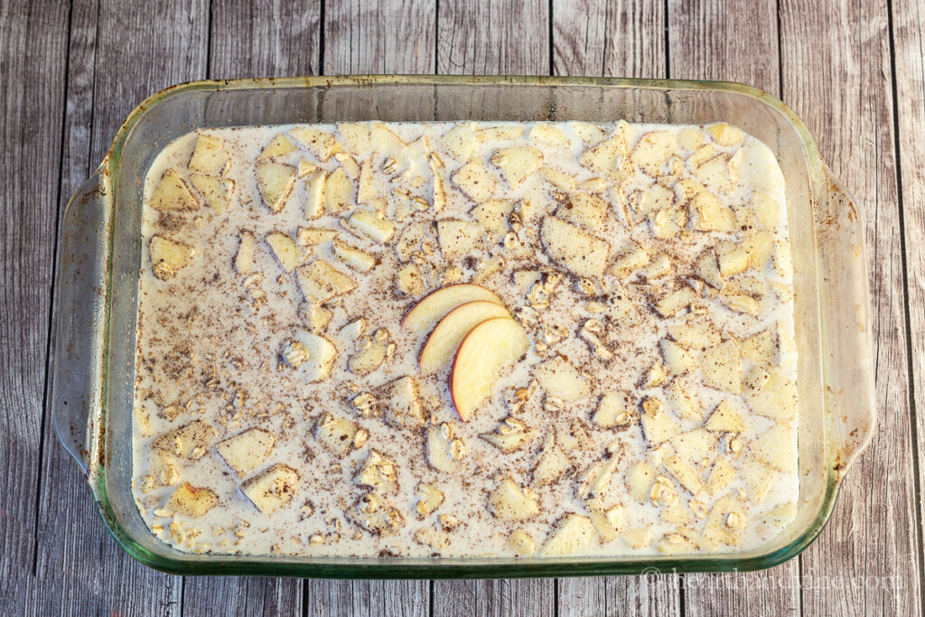 A 9 x 13 inch glass casserole dish filled with apple pie oatmeal prior to baking.