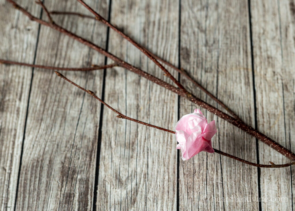 Paper cherry blossom glued to a bud on the branch.