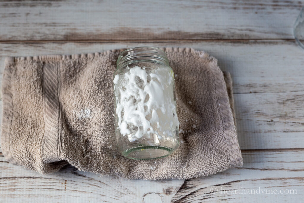 A glass jar on a washcloth with a paste of baking soda and water.
