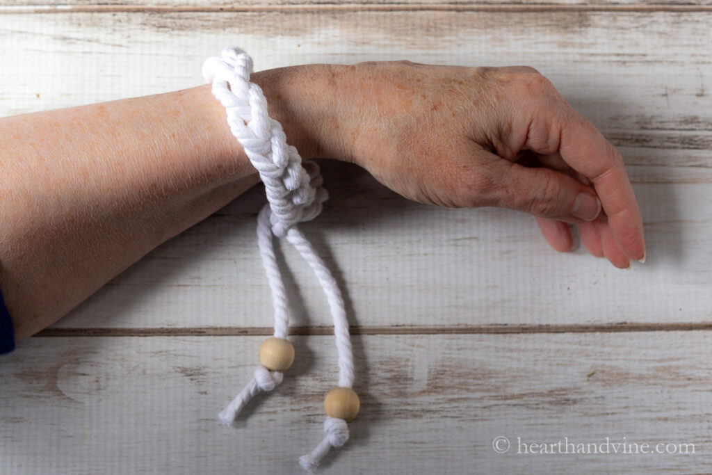 White cord bracelet on a wrist with wooden beads.