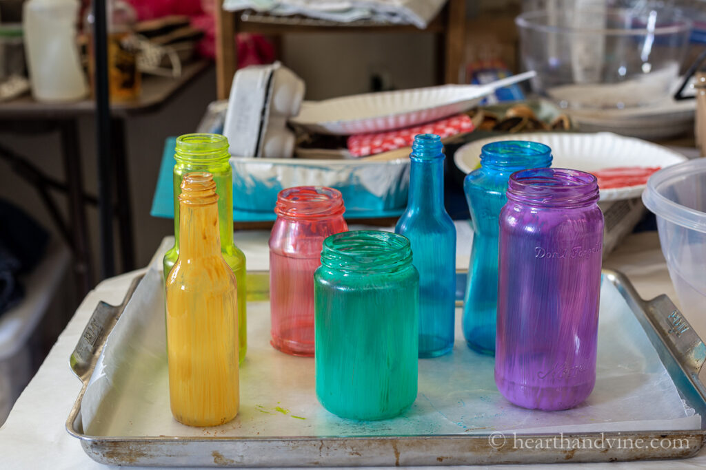 Different colored tinted glass jars on a baking sheet.