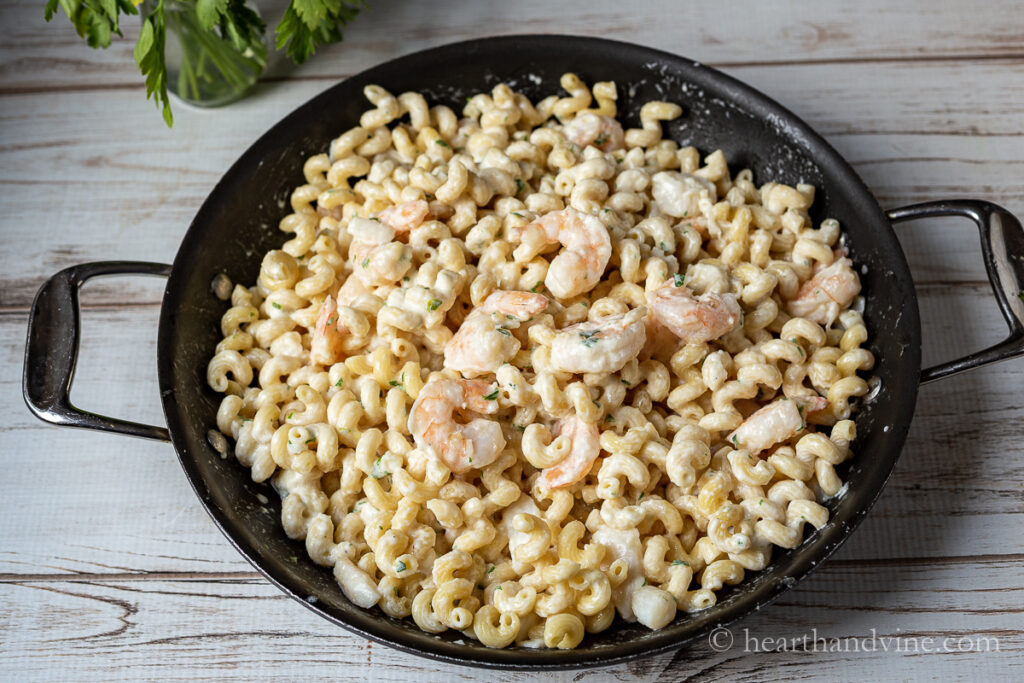 Extra large skillet with seafood alfredo pasta including shrimp and scallop pieces.