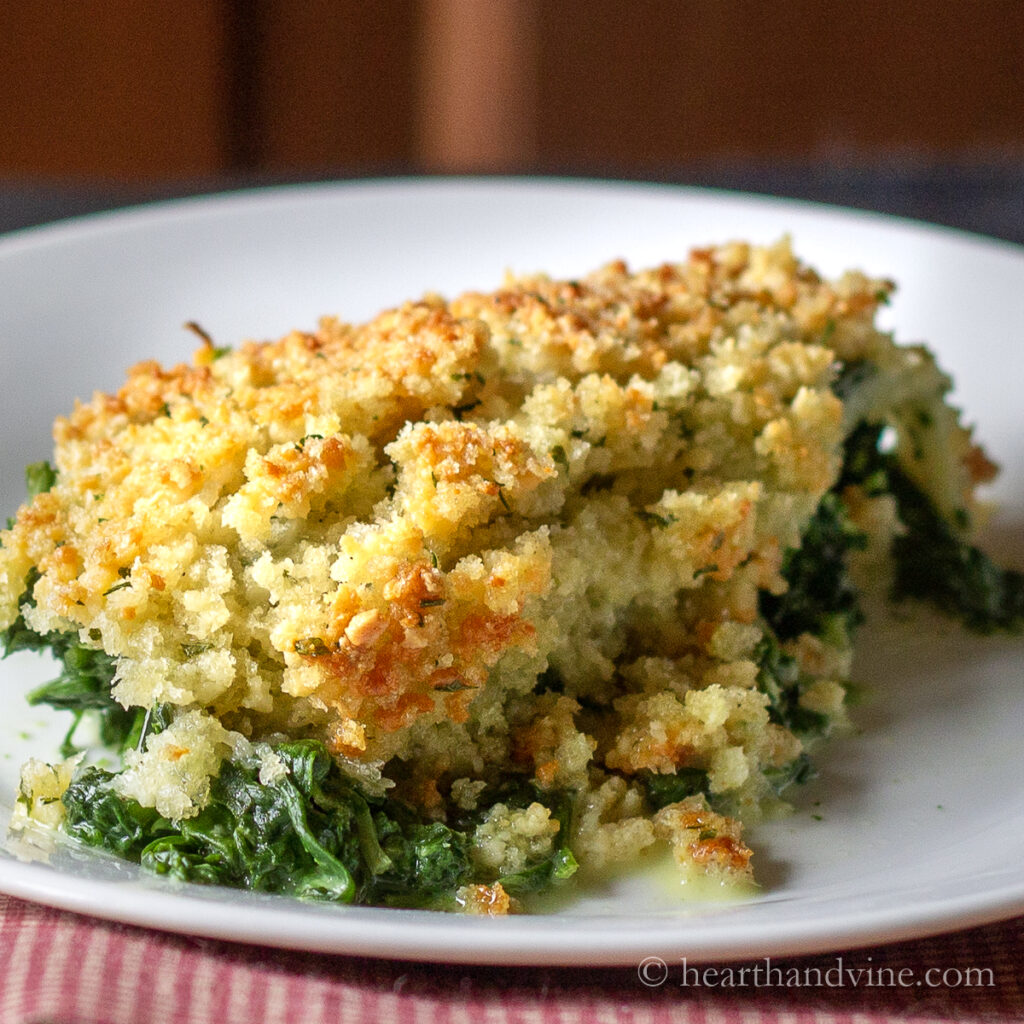 Serving of creamy spinach casserole on a white plate.
