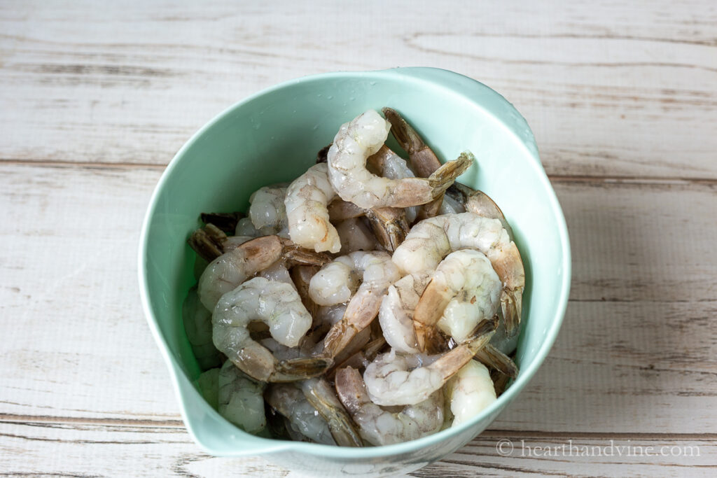 Bowl of thawed raw shrimp with tails on.