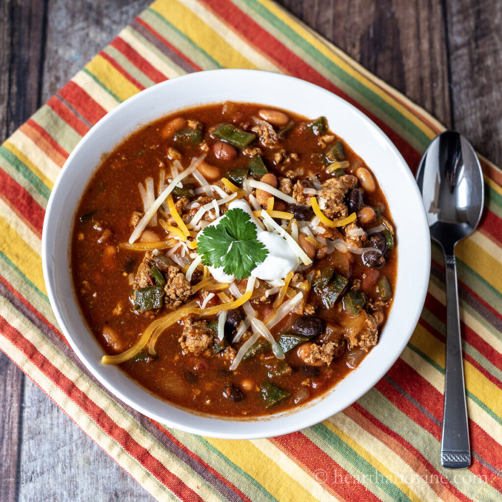 Serving of ground turkey chili in a white bowl with a spoon. 