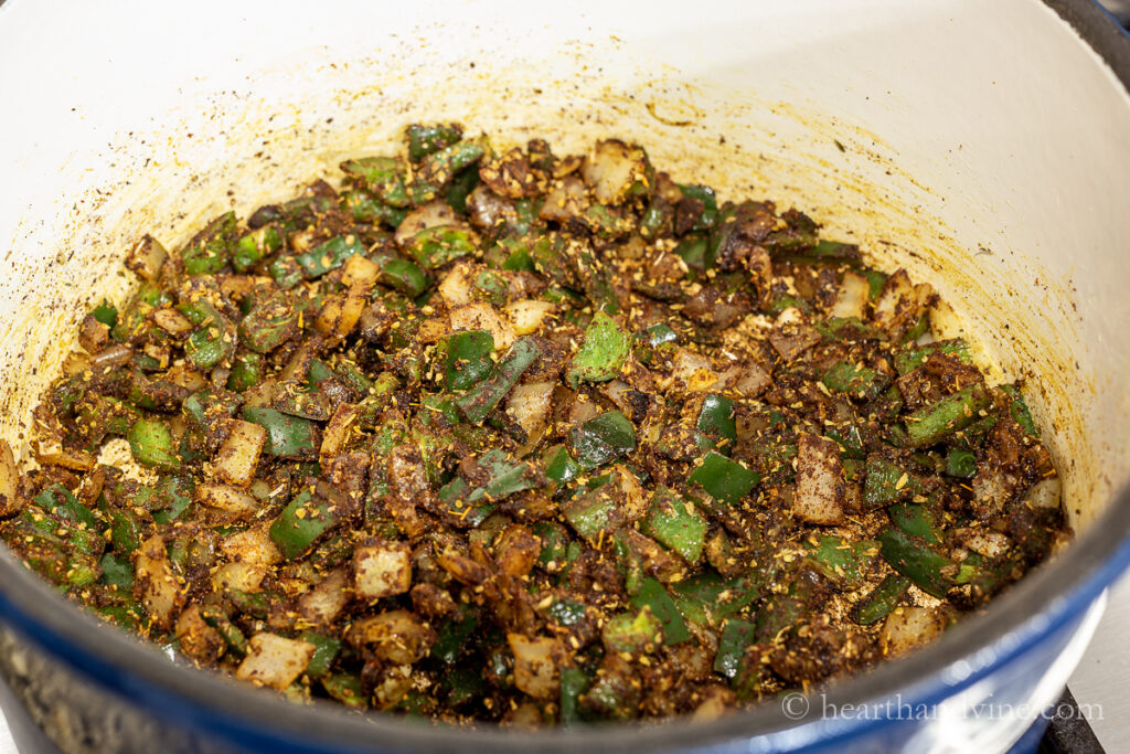 Poblano peppers, onions, garlic and spices cooking in the bottom of a large pot.