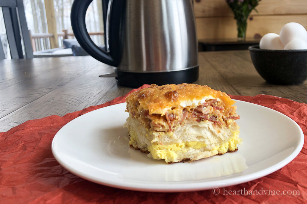 A serving of a bacon, egg and biscuit casserole on a white plate on a table.