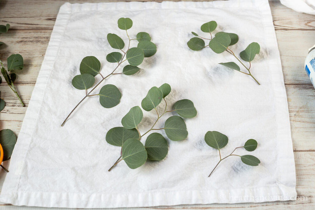 White napkin with fresh branches of eucalyptus set on top.