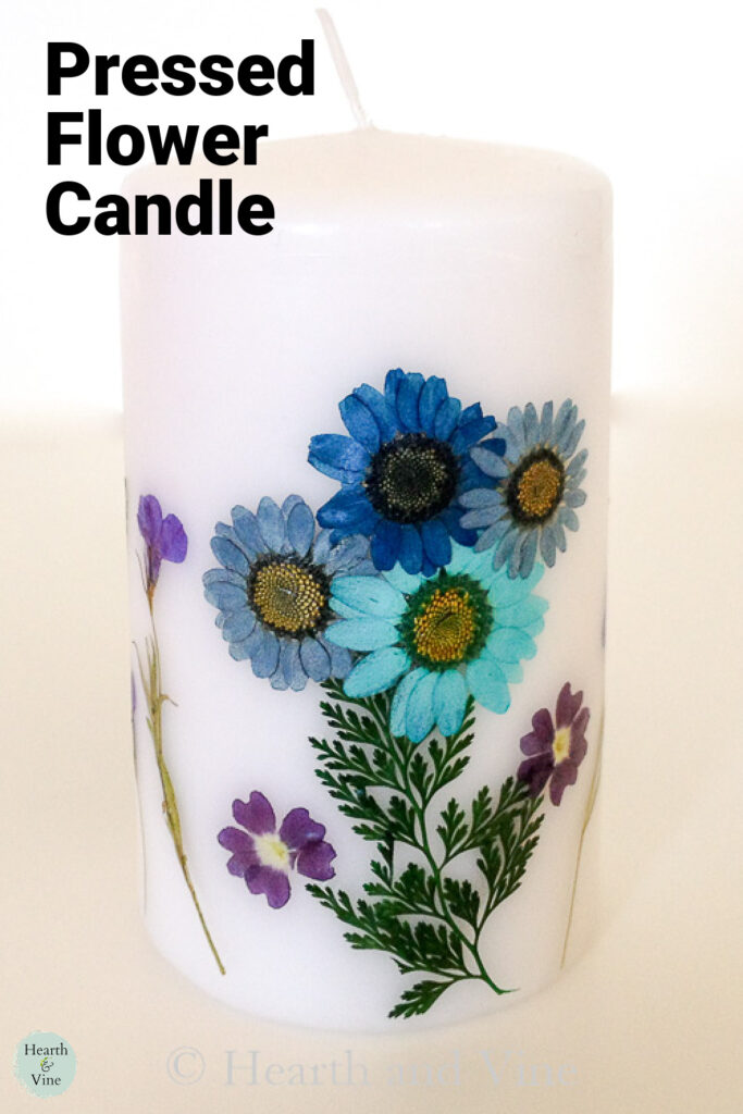 Tall white pillar candle decorated with pressed flowers.