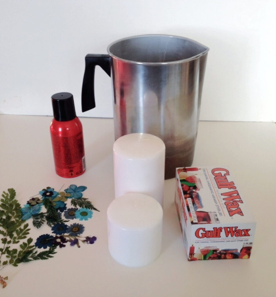 Pressed flowers, pillar candles, paraffin wax, spray adhesive and a candle pitcher.