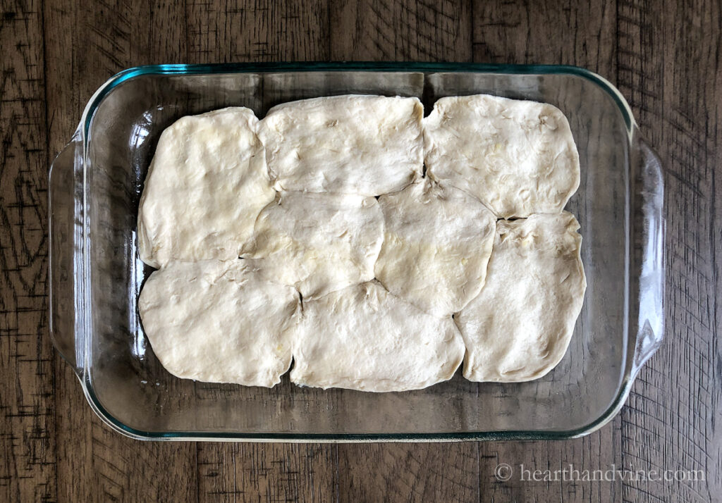 Eight biscuits spread to cover a 9 x 13 inch glass baking pan.