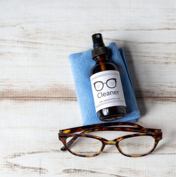 eyeglass cleaner bottle on a cloth with glasses in front.