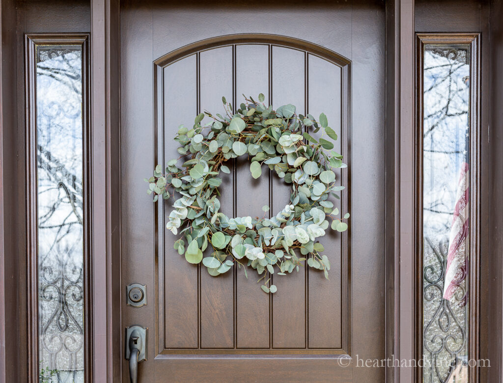 Fresh grapevine eucalyptus wreath on a brown front door.