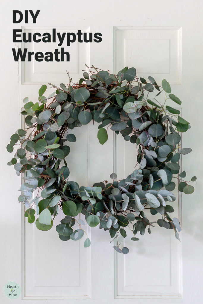Fresh eucalyptus wreath with a grapevine base on a white door.