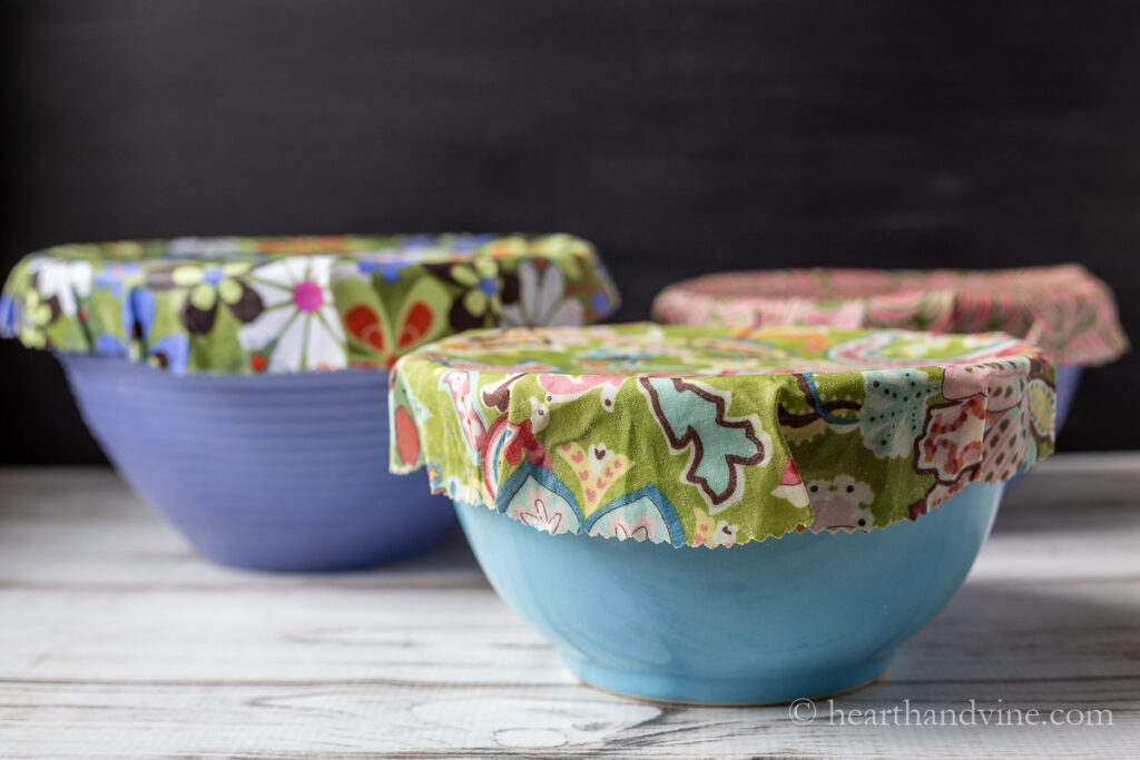 Three blue ceramic bowls with multi-colored beeswax covers.