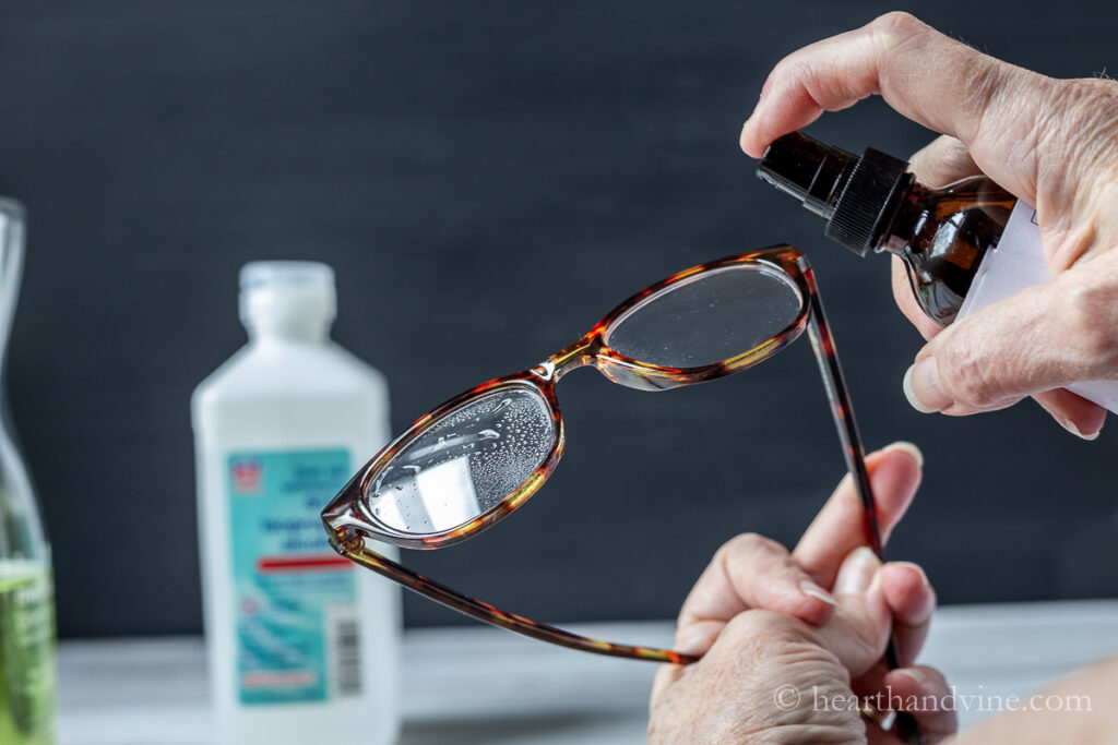 Spraying glasses cleaner onto glasses.