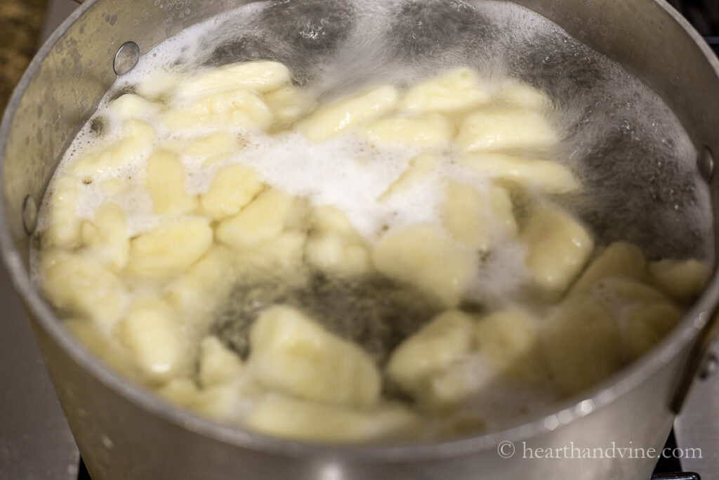 Gnocchi floating to the top of a pot of boiling water.