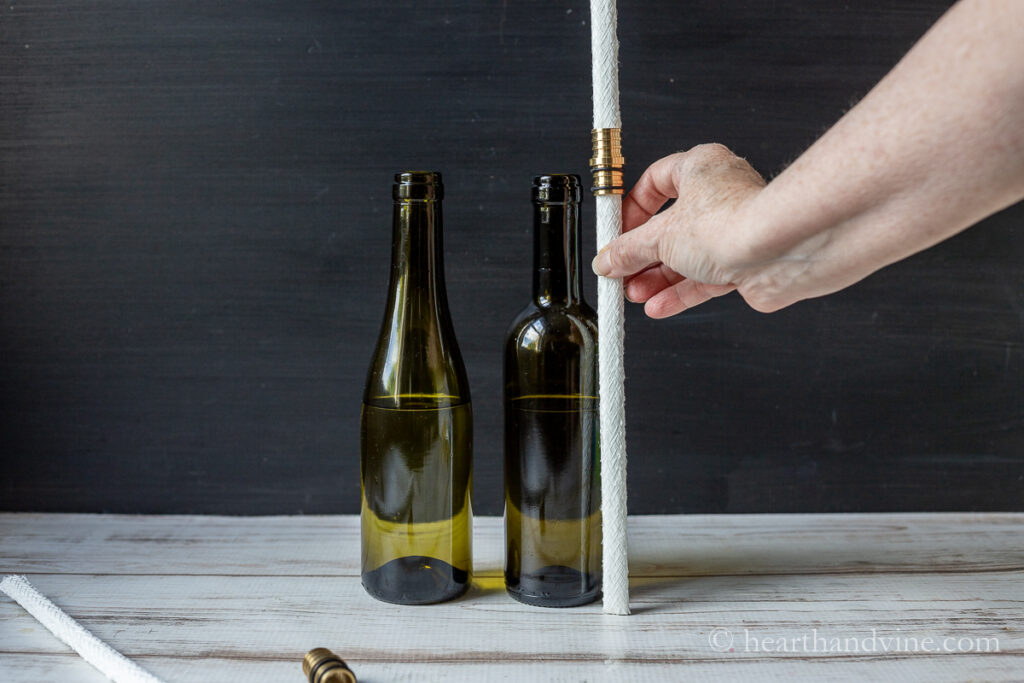 Measuring the height of a wick next to the wine bottle.