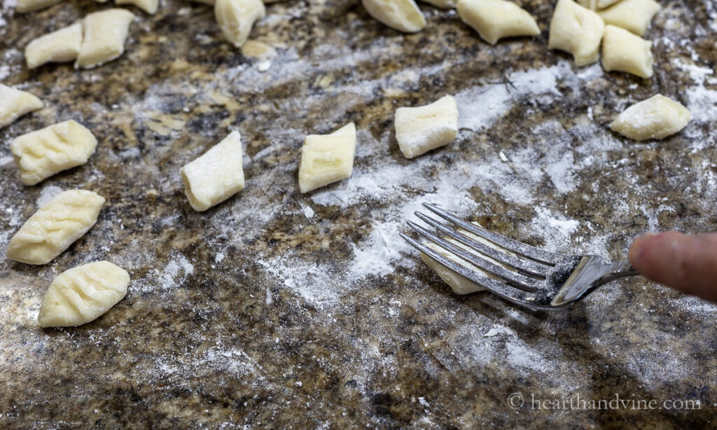 Using the back of a fork to roll the gnocchi and make indentations.