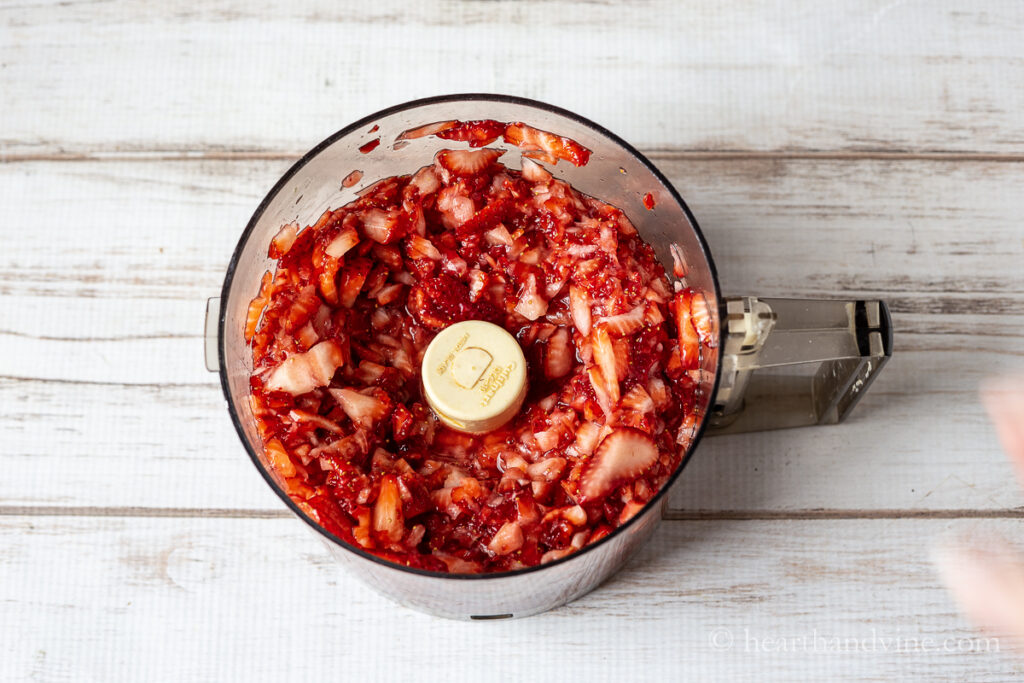 Food processor with chopped up strawberries.