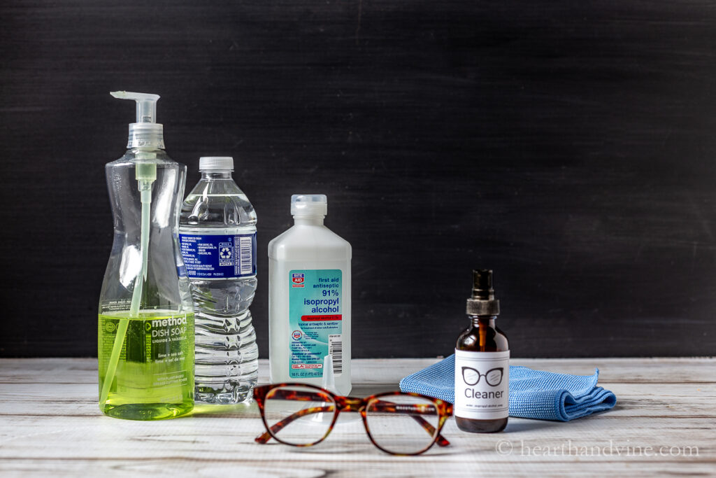 Eyeglasses, spray bottle of homemade eyeglass cleaner, isopropyl alcohol, bottle of water and dish soap.