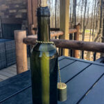 Small green wine bottle tiki torch on an outdoor deck.