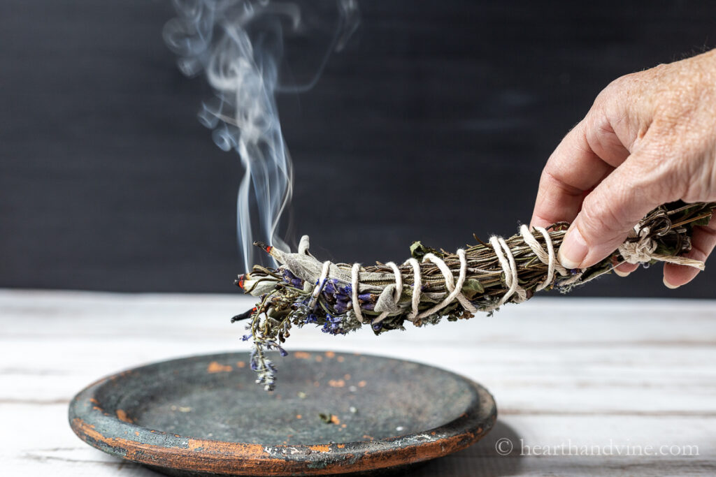 DIY smudge stick burning over a plate.