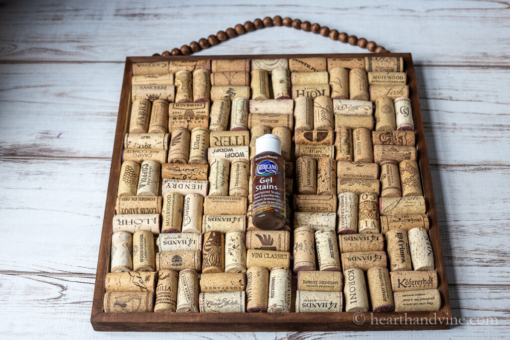 Brown gel stain bottle on corks in a wooden frame.